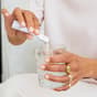 Donna che versa The Solution in un bicchiere d'acqua